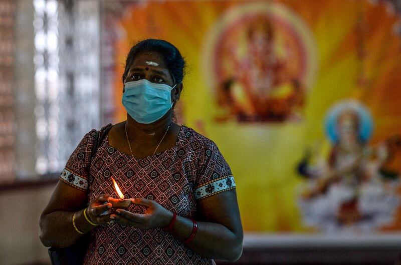 A Hindu devotee offers prayers while holding an oil lamp or diya during Diwali, the Hindu festival of lights, at a temple in Colombo on November 14, 2020. / AFP / LAKRUWAN WANNIARACHCHI
