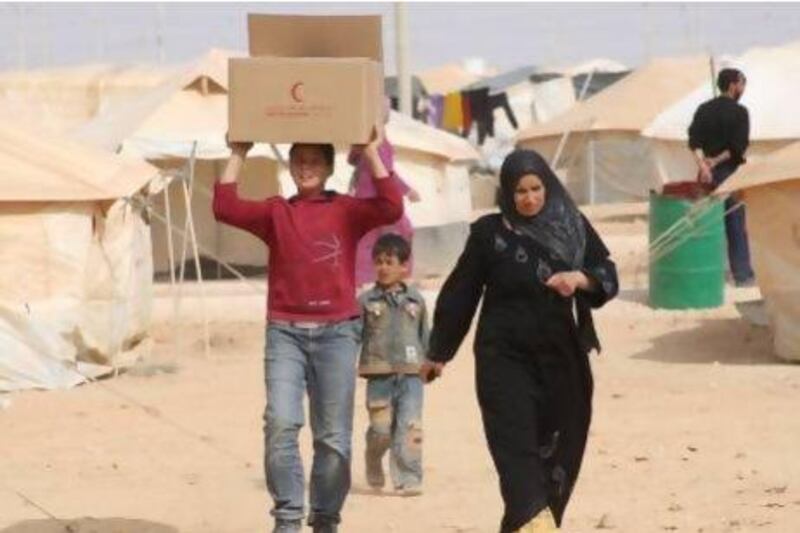 Syrian refugees, who fled the unrest in Syria, carry a box of food distributed by the United Arab Emirates Red Crescent ahead of Eid al-Adha (Feast of Sacrifice) at the Al Zaatri refugee camp in the Jordanian city of Mafraq, near the border with Syria. Reuters / Majed Jaber