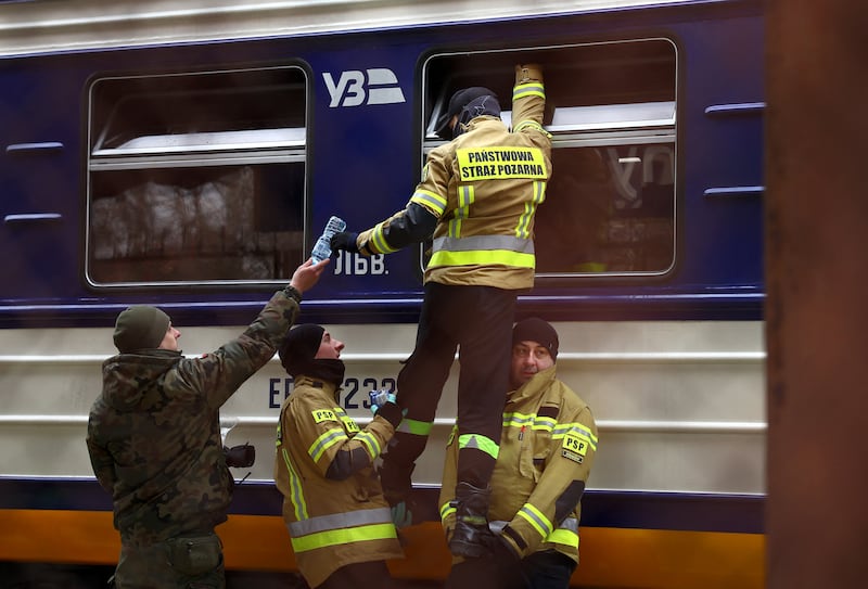 Firefighters hand water to people in a Ukrainian train full of refugees in Przemysl, Poland. Reuters