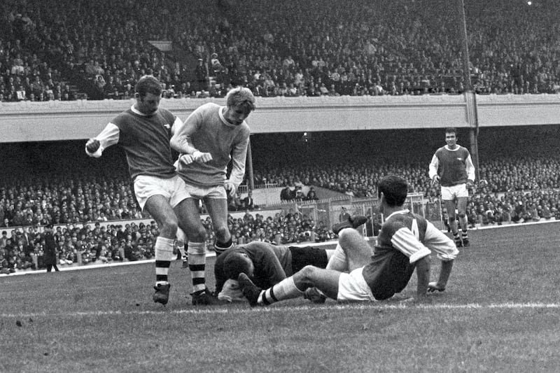 Arsenal goalkeeper Jim Furnell gathers the ball under pressure from teammates Terry Neill (l), Frank McLintock (r) and Manchester City's Colin Bell (c).