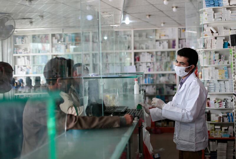 A Yemeni pharmacist serves his customers behind a glass shield  at a pharmacy in Sanaa, Yemen. AP Photo