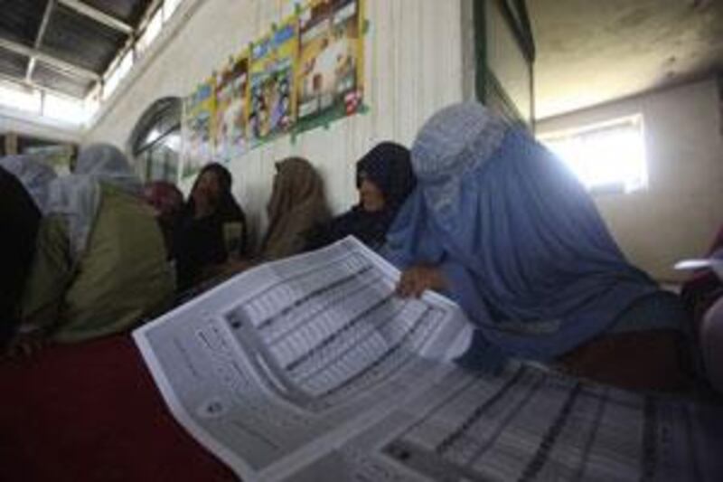 A woman reviews copies of ballot papers during an election awareness programme on the outskirts of Kabul.