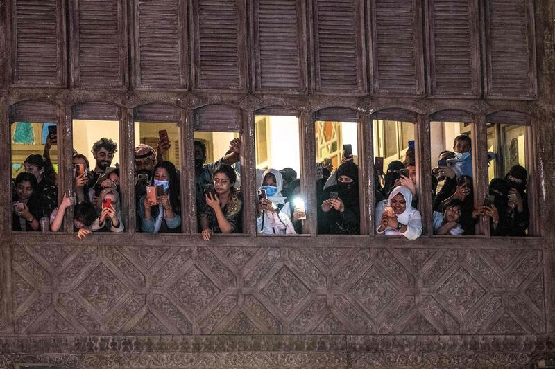 Fans watching from a nearby building take pictures with their telephones as stars walk the red carpet. AFP