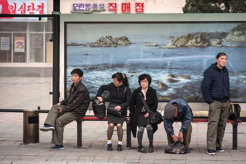 In a photo taken on April 8, 2017 commuters wait at a bus stop in Pyongyang.
Buses are by far the most common means of public transport in the capital of around three million people, where access to private cars is rare, and offer the most extensive network. Tickets cost 5 won each – less than 0.1 US cents at free-market rates, making journeys virtually free. The city is one where everyone almost always appears to have a purpose, whether going to or from work, or taking part in some kind of group activity. At bus stops, though, commuters are forced to disrupt that process as they wait for a vehicle. It is a moment that reveals their private interests – whether talking to friends and colleagues, pensively watching the world go by, or sometimes playing with a smartphone. / AFP PHOTO / Ed JONES