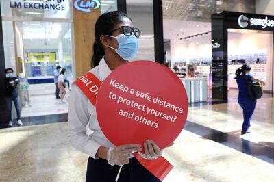 FILE PHOTO: A woman wearing a protective face mask and gloves holds a sign at Mall of the Emirates after the UAE government eased a curfew and allowed stores to reopen, following the outbreak of the coronavirus disease (COVID-19) in Dubai, United Arab Emirates May 5, 2020. REUTERS/Ahmed Jadallah/File Photo