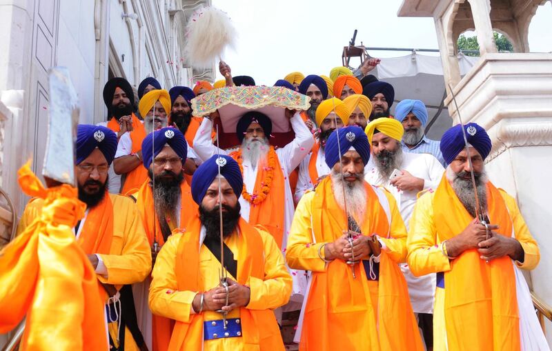 A Sikh priest (C), carries the Sri Guru Granth Sahib ji, the holy book of Sikh religion, on his head during a procession at the Golden Temple in Amritsar, India.  EPA