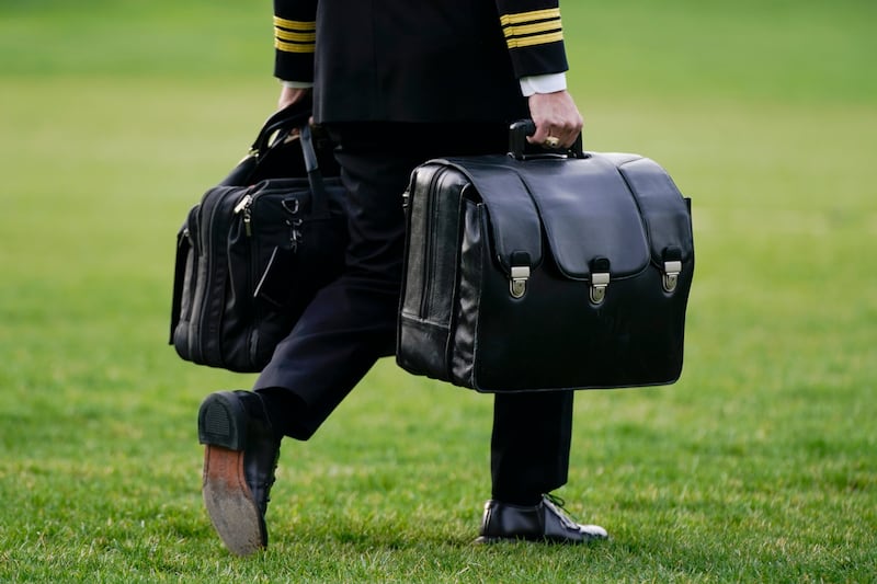 A military aide carries the 'football', which contains nuclear launch codes, before boarding 'Marine One' behind US President Joe Biden. AP