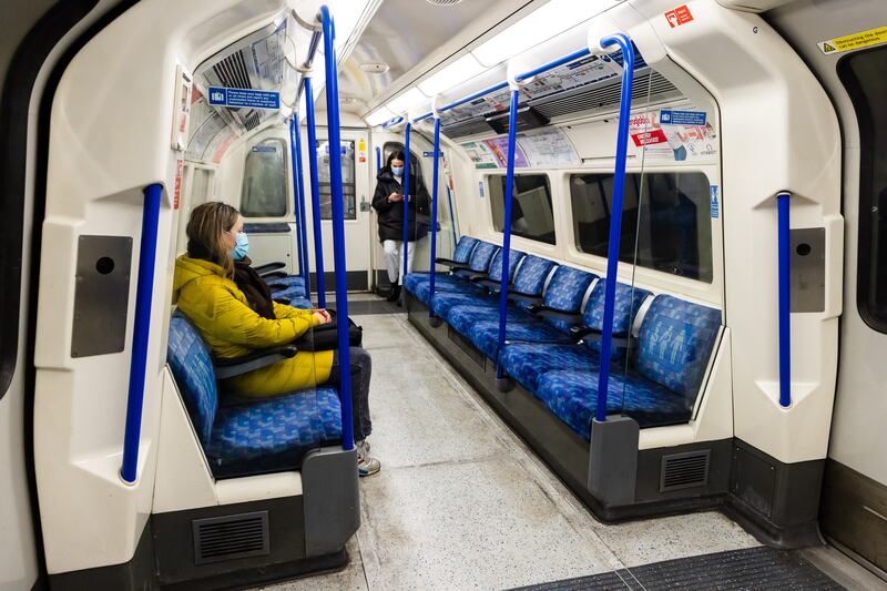Two women wearing face masks sit in an empty Tube train in London. The latest figures indicate that 1.2 million Britons have tested positive for Covid-19 over the past week. EPA
