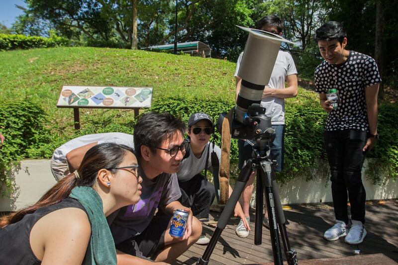 People look through a camera with a homemade solar filter to watch as the moon moves in front of the sun in a rare "ring of fire" solar eclipse in Singapore.  AFP