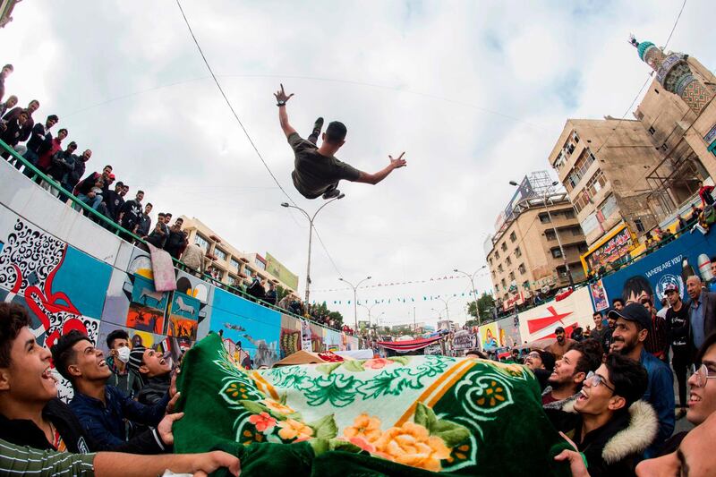 A young protester is blanket-tossed into the air by fellow demonstrators in Tahrir Square. AFP