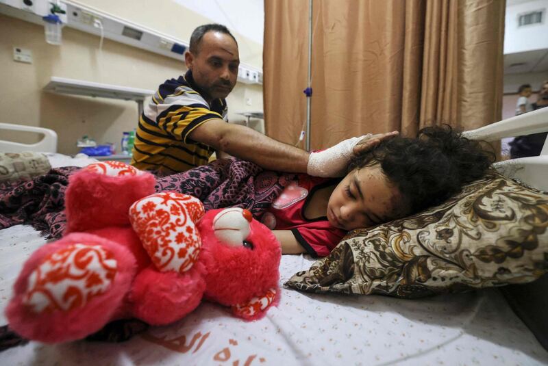 TOPSHOT - Palestinian Ryad Eshkuntana, checks his daughter Suzy, as they receive medical care at Al-Shifa hospital in Gaza City, on May 19, 2021, after his wife and other children were killed in an Israeli air strike. Deafening air strikes and rocket fire once more shook Gaza overnight and early today amid an international diplomatic push to broker a ceasefire after more than a week of bloodshed. / AFP / MAHMUD HAMS
