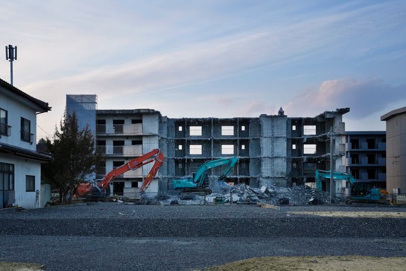 Heavy-duty machinery sits unattended in the evening beside a building that is set to be torn down. AP