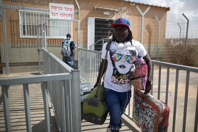 An African asylum seeker carries belongings following his release from the Holot Detention Centre in Israel's Negev desert on August 25, 2015. Menahem Kahana / AFP

