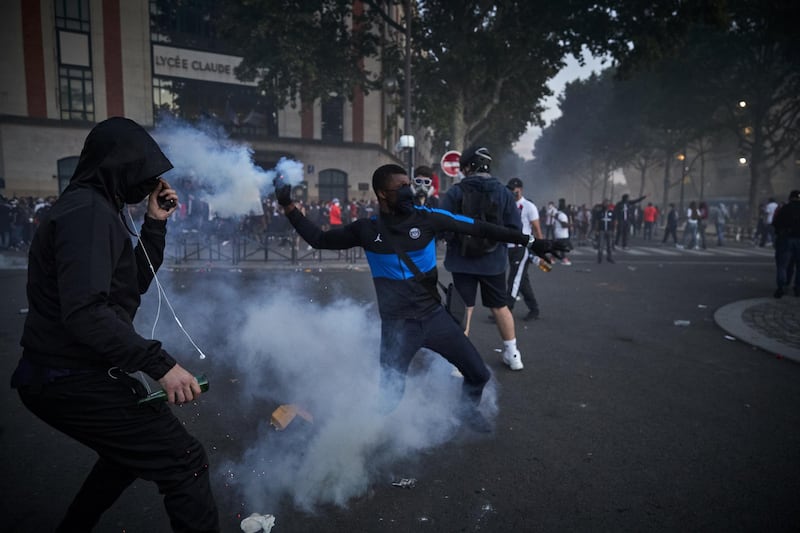 A Paris Saint-Germain fan throws a tear gas shell towards French riot police. Getty