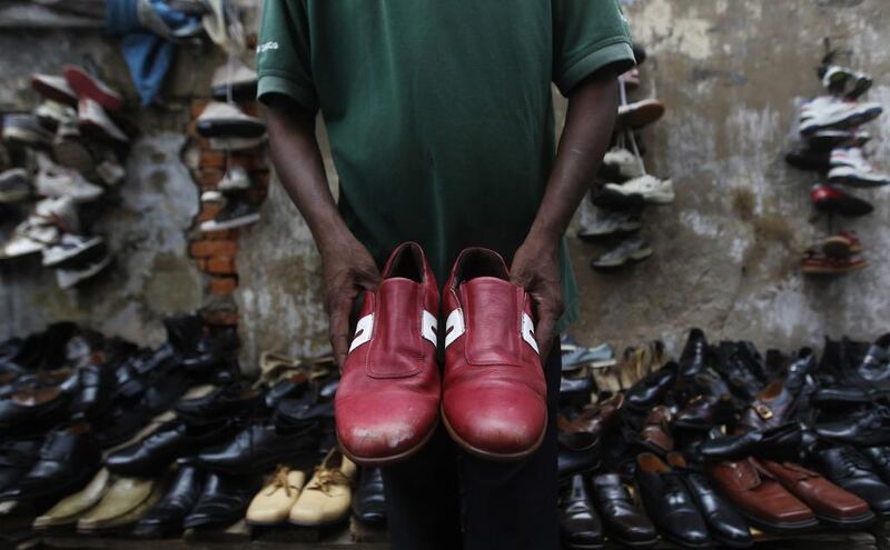 A vendor shows a pair of used shoes at his stall on the side of a lane, near a main market in Colombo. Dinuka Liyanawatte / Reuters