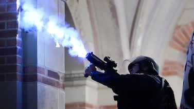 A police officer launches a smoke bomb on the UCLA campus during a raid on a pro-Palestinian encampment on Thursday. AP
