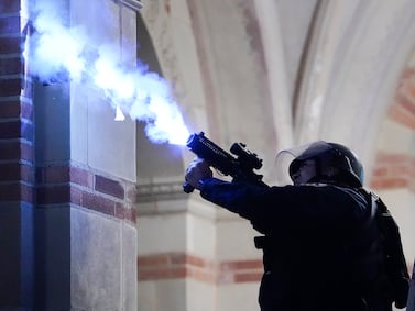 A police officer launches a smoke bomb on the UCLA campus during a raid on a pro-Palestinian camp on Thursday. AP