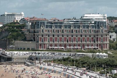 People swim in the sea and walk on the beach in front of the "Hotel du Palais" in Biarritz, on August 13, 2019. The French southwestern seaside resort of Biarritz, known in France as the 'Cote Basque', will host the 45th Group of Seven (G7) nations annual summit from August 24-26, 2019. / AFP / IROZ GAIZKA
