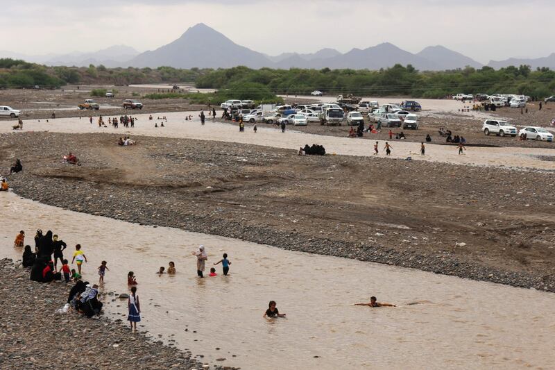 People cool down in a stream of floodwater after heavy rain in Lahj, Yemen.