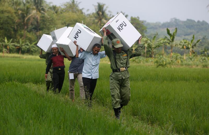 epa07509371 District employees carry ballot boxes through a field as they distribute them to pollings center at villages in the city of Bogor, Indonesia, 16 April 2019. Indonesia will hold its general elections on 17 April, during which the president, vice president, and members of the People's Consultative Assembly will be elected.  EPA/ADI WEDA