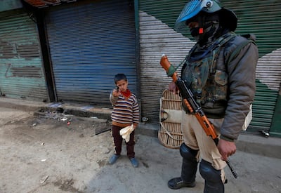 A boy plays with his toy pistol next to an Indian policeman standing guard in front of closed shops during a strike called by Kashmiri separatists against the arrest of Yasin Malik, Chairman of Jammu Kashmir Liberation Front (JKLF), a separatist party, in Srinagar March 8, 2019. REUTERS/Danish Ismail     TPX IMAGES OF THE DAY