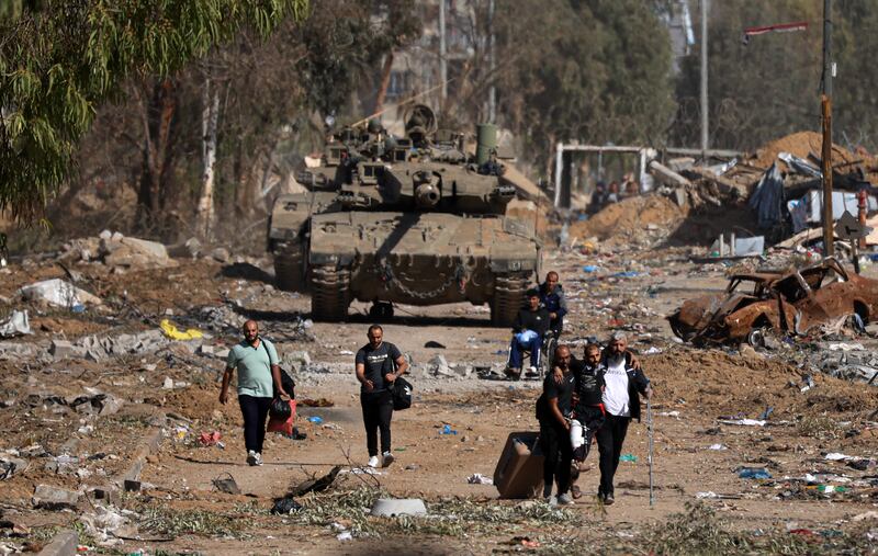 Palestinians fleeing the north trudge along the Salaheddine road in the southern outskirts of Gaza city, with Israeli tanks in the background. AFP