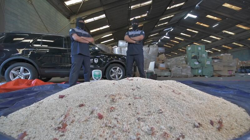 Saudi customs officials stand in front of a mound of seized Captagon pills