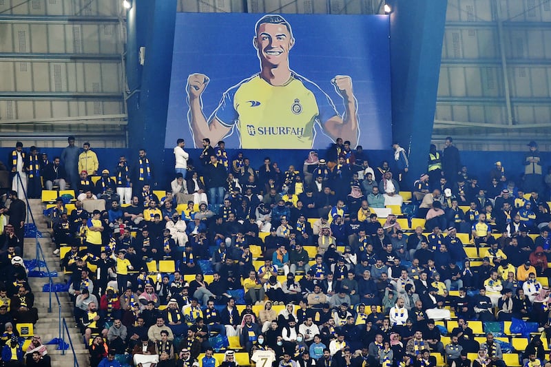 Al Nassr fans sit under a giant poster of Cristiano Ronaldo. AP 