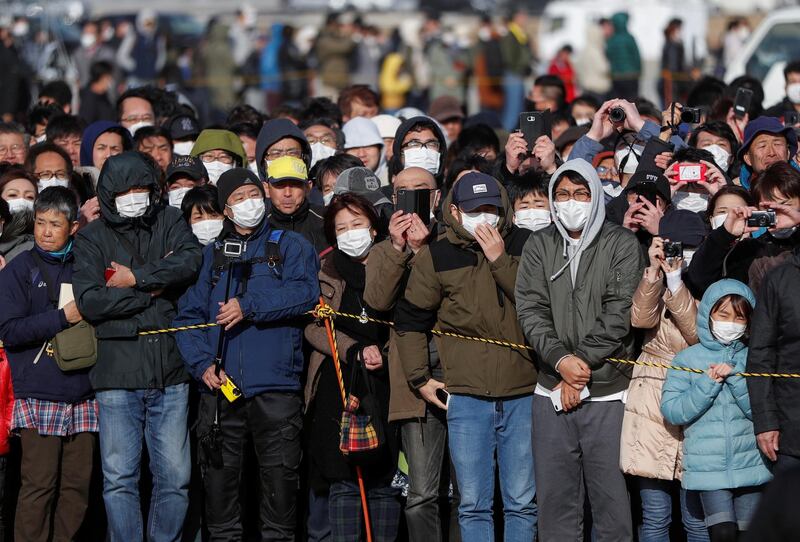 People wear protective face masks following the outbreak of the coronavirus disease  as they try to watch the Olympic cauldron during the Tokyo 2020 Olympic's Flame of Recovery tour  in Ishinomaki, Miyagi prefecture, Japan. Reuters