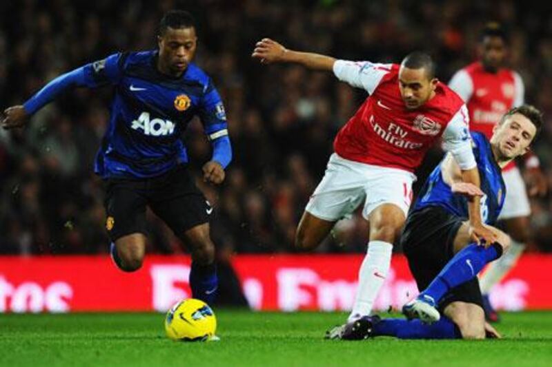 Theo Walcott of Arsenal splits Manchester United players Patrice Evra, left, and Michael Carrick.