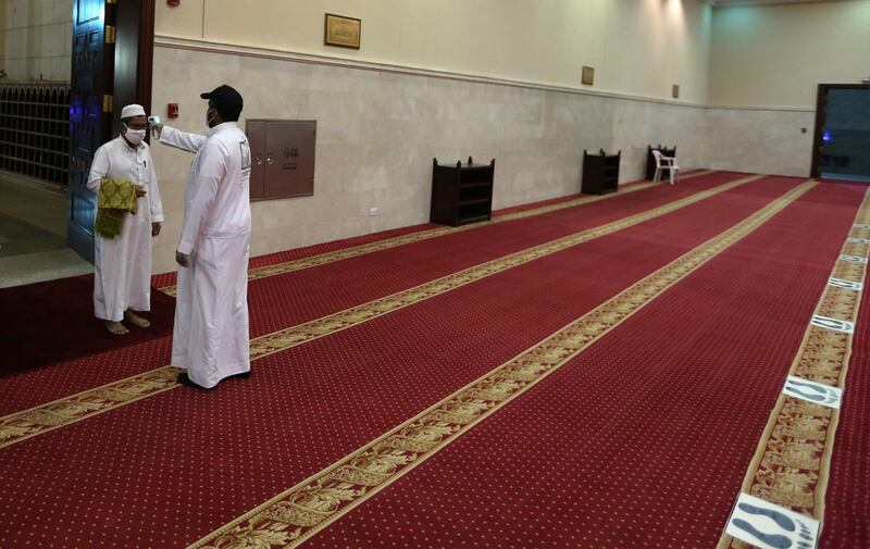 A volunteer checks the temperature of a man as he arrives to perform the dawn prayer at a mosque in the Saudi city of Makkah. AFP