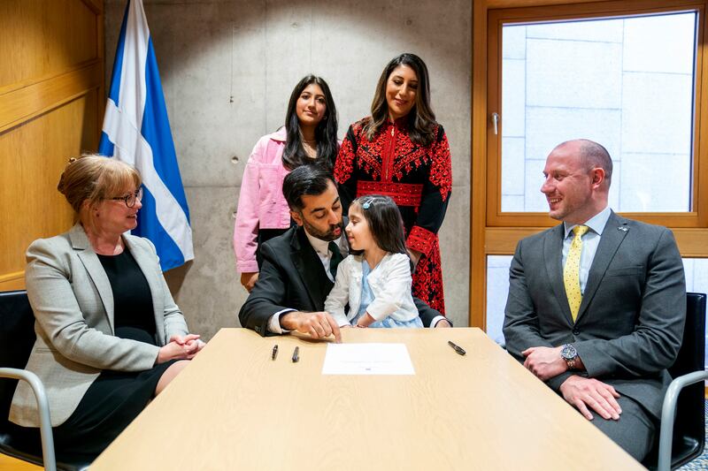 Later that day, the newly elected leader of the Scottish National Party, Humza Yousaf, centre, signed the nomination form to become First Minister for Scotland alongside his family, at the Scottish Parliament in Edinburgh. AP