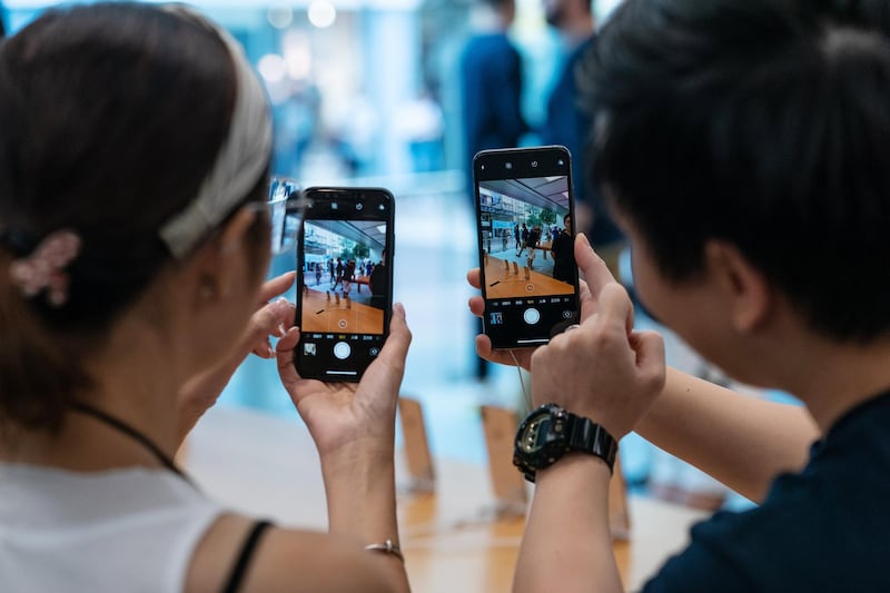 An employee, right, demonstrates the camera function of the iPhone XS Max, right, and the iPhone XS at an Apple store during its launch in Hong Kong, China. Bloomberg