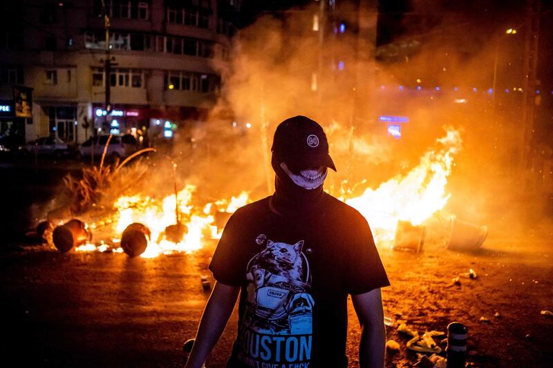 A protester walks past a fire during clashes with police at a demonstration against the government in front of the Romanian Government headquarters, in Bucharest. AFP