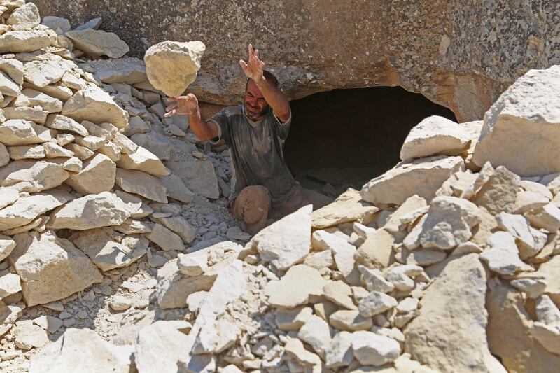 Abu Ahmad, a displaced Syrian from Termala clears material as he digs a cave for shelter in the village of Kafr Lusin near the Syria-Turkey border, on September 9, 2019. The 49-year-old father of three has dug a cave for his family in the village of Kafr Lusin, three months after fleeing bombardment of his hometown of Termala, south of Idlib. / AFP / Zein Al RIFAI
