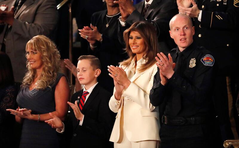 Preston Sharp, second left, who organised the placing of US flags at the graves of 40,000 veterans, applauds with first lady Melania Trump and Officer Ryan Holets of the Albuquerque, New Mexico, police department as Donald Trump delivers his State of the Union address. Leah Millis / Reuters