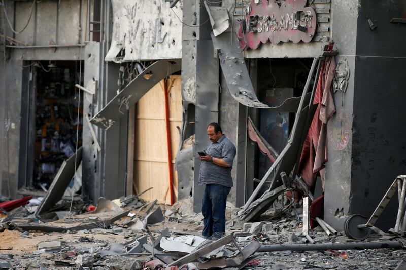 A Palestinian man stands outside a damaged shops in the aftermath of Israeli air strikes that destroyed a tower building. Reuters