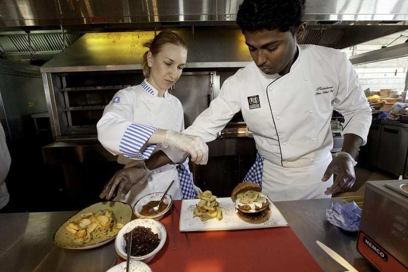 Chef Vlassia Anagnostou, left, and chef Praba Manickam cook the mousaka hamburger at the Eat Greek restaurant at the new Beach Mall in JBR. Jaime Puebla / The National 