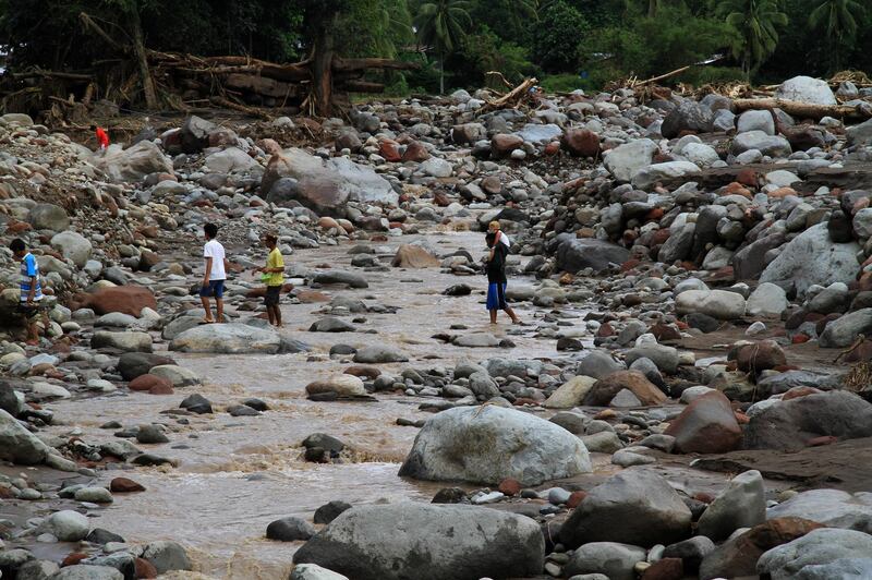 Residents walk on boulders swept by flashfloods in a village in Salvador, Lanao del Norte in southern Philippines . Richel V. Umel / Reuters