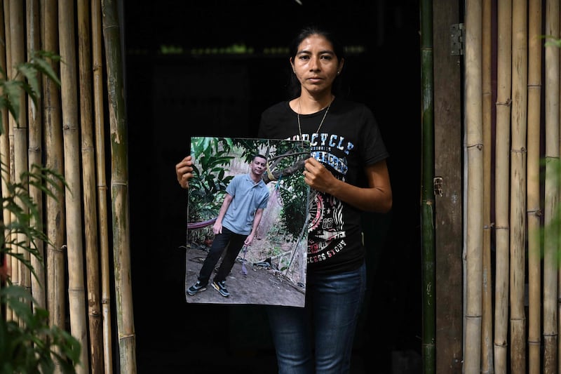 A woman poses with a picture of her husband who was captured under the state of emergency and later died in prison. AFP