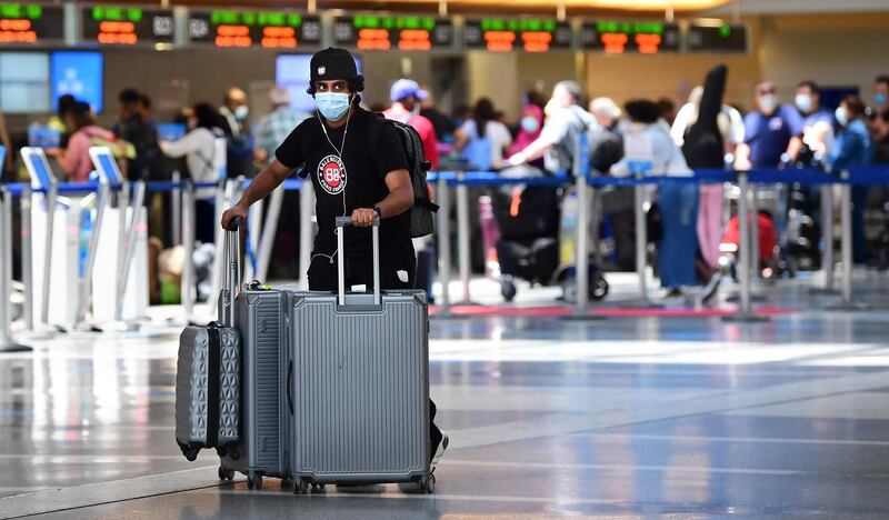 A man pushes his bags on the departures level at Los Angeles International Airport (LAX) on May 27, 2021 in Los Angeles as people travel for Memorial Day weekend, which marks the unofficial start of the summer travel season. Global air passenger numbers could rebound from the coronavirus pandemic to top 2019 levels by 2023, the International Air Transport Association predicted on May 26. / AFP / Frederic J. BROWN
