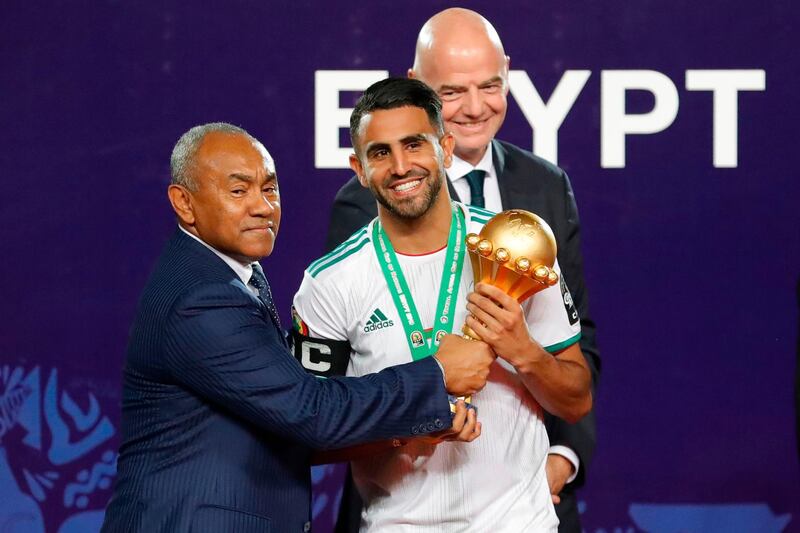 Algeria's forward Riyad Mahrez (C) receives the trophy from Confederation of African Football (CAF) President Ahmad Ahmad (L) during the 2019 Africa Cup of Nations (CAN) Final football match between Senegal and Algeria at the Cairo International Stadium in Cairo on July 19, 2019.  / AFP / Khaled DESOUKI
