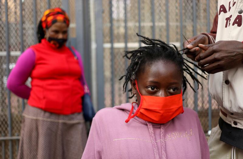 A mother looks on as her daughter gets a haircut by roadside hairdresser  in Johannesburg, South Africa. Reuters