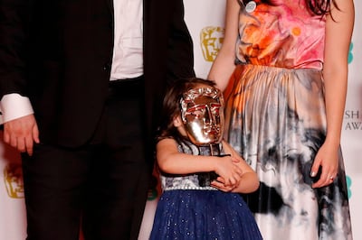 Sama (C) holds the award over her face as (L-R) Hamza al-Kateab and Syrian filmmaker Waad al-Kateab pose during the award for a Documentary for 'For Sama' at the BAFTA British Academy Film Awards at the Royal Albert Hall in London on February 2, 2020.   / AFP / Adrian DENNIS
