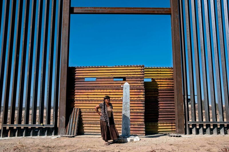 Maria Guadalupe Arvallo, a member of Pai-Pai indigenous group, stands next to a section of the US-Mexico border fence at indigenous lands, east of Tecate, Baja California State, Mexico.  Indigenous communities who live along the Mexico/US border are struggling due to US President Donald Trump's reinforcement and expansion of the border wall and the environmental and cultural affectations caused by its construction. AFP