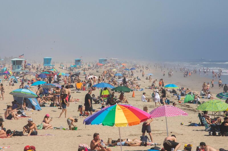 (FILES) In this file photo taken on April 25, 2020 People enjoy the beach amid the novel coronavirus pandemic in Huntington Beach, California on April 25, 2020. Governor Gavin Newsom on April 27, 2020 admonished Californians who flocked to beaches at the weekend, warning that their behavior could reverse progress made in combating the coronavirus pandemic. / AFP / Apu GOMES

