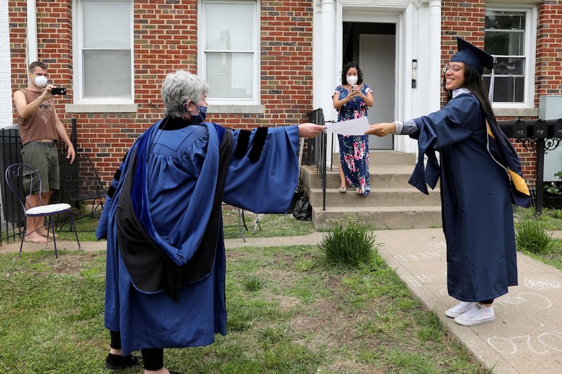 George Washington University graduate Catalina Perez, right, receives a copy of her diploma from neighbour Paula Lytle as they keep a social distance at a surprise graduation party for Perez, who completed her undergraduate studies in International Affairs across the span of 10 years only to miss her commencement due to coronavirus, in Washington, US. Reuters