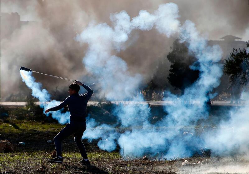 A Palestinian protester hurls a tear gas canister back towards Israeli troops during clashes near an Israeli checkpoint in the West Bank city of Ramallah on December 8, 2017.
Israel deployed hundreds of additional police officers following Palestinian calls for protests after the main weekly Muslim prayers against US President Donald Trump's recognition of Jerusalem as Israel's capital. / AFP PHOTO / ABBAS MOMANI