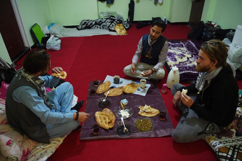 In this photo taken on November 11, 2018, Afghan Couchsurfing host Naser Majidi (C), 27, eats brekfast with his guests Norwegian tourist Jorn Bjorn Augestad (R), 29, and Dutch tourist Ciaran Barr, 24, at a house in Kabul.
 Once a popular stop on the well-worn hippy trail between Europe and South Asia in the 1970s, Afghanistan has seen the number of foreign travellers crossing its borders dwindle in the past four decades of almost non-stop conflict. But dozens still make the dangerous journey every year, ignoring clear warnings from their own governments to stay away from a country infested with suicide attackers, kidnappers and armed robbers, and which by some estimates is now the world's deadliest conflict zone.  - TO GO WITH AFP STORY AFGHANISTAN-LEISURE,FEATURE BY ALLISON JACKSON
 / AFP / WAKIL KOHSAR / TO GO WITH AFP STORY AFGHANISTAN-LEISURE,FEATURE BY ALLISON JACKSON
