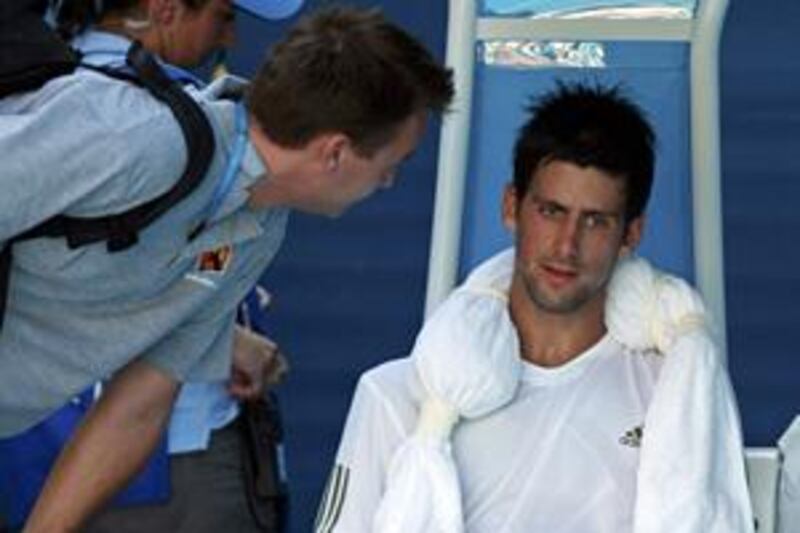 Novak Djokovic talks to his trainer during a medical break in his men's singles quarter-final match against Andy Roddick. The Serb Djokovic was forced to retire through injury after the third game of the fourth set.